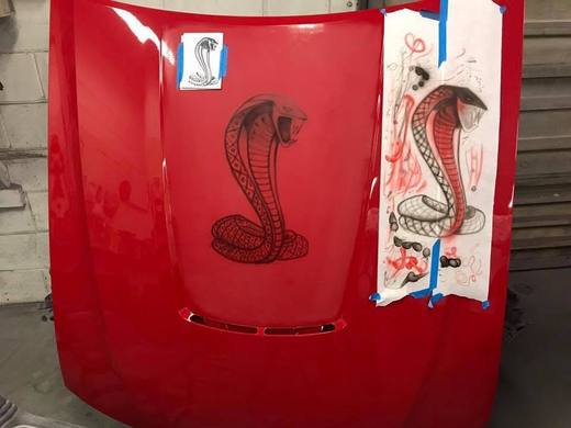 A Cobra snake stencilled onto a red hood, masking still on